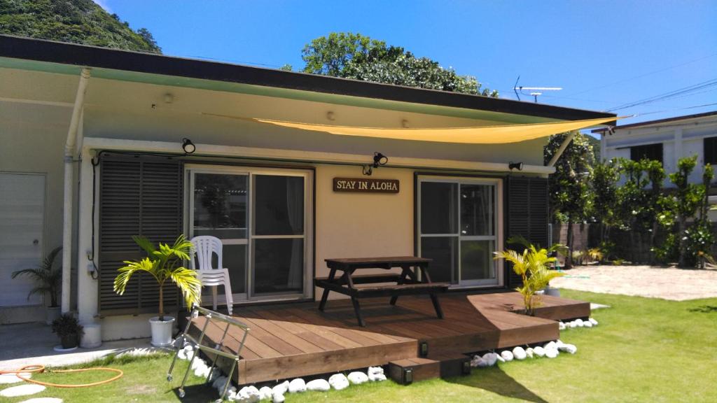 ein Haus mit einer Terrasse mit einem Tisch und einer Bank in der Unterkunft STAY IN ALOHA in Tokashiki