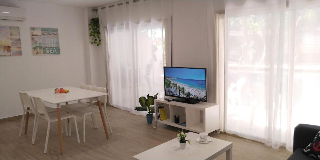uma sala de estar com uma televisão e uma mesa em SCALA Apartaments em Salou