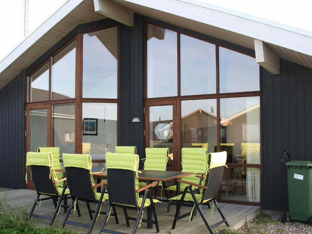a wooden table and chairs on a patio with glass windows at 6 person holiday home in Ulfborg in Thorsminde