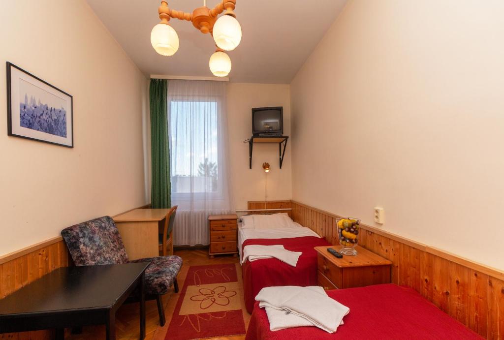 Cette chambre comprend 2 lits et une table. dans l'établissement Laterum Economy, à Pécs
