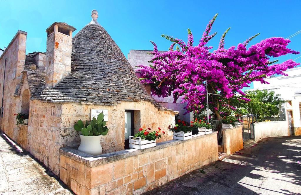 un antiguo edificio con un árbol con flores púrpuras en Trulli Antica Fonte, en Alberobello