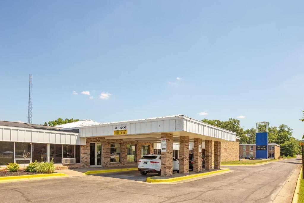 een gebouw met een auto geparkeerd op een parkeerplaats bij OYO Hotel Mona Lake Muskegon in Muskegon