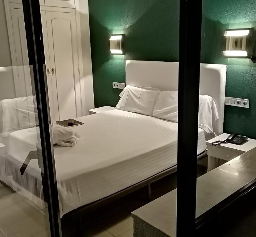 a bedroom with a large white bed with a green wall at Balneario de Ledesma in Vega de Tirados