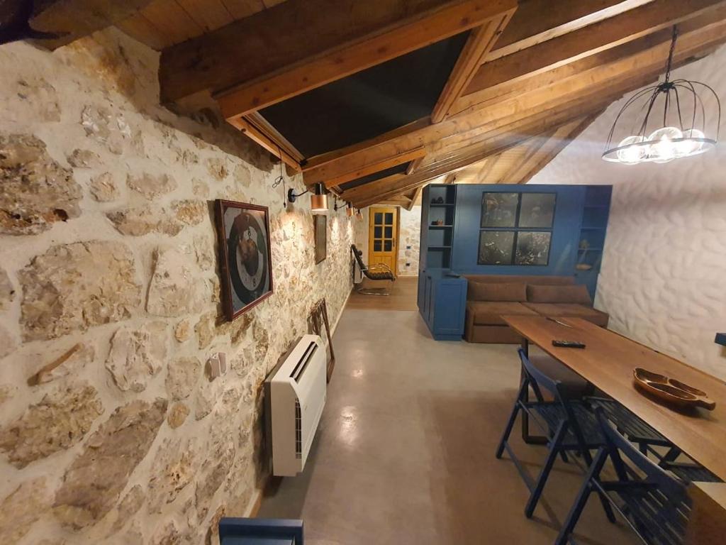 a room with a stone wall with a table and chairs at Roots Dhermi in Dhërmi