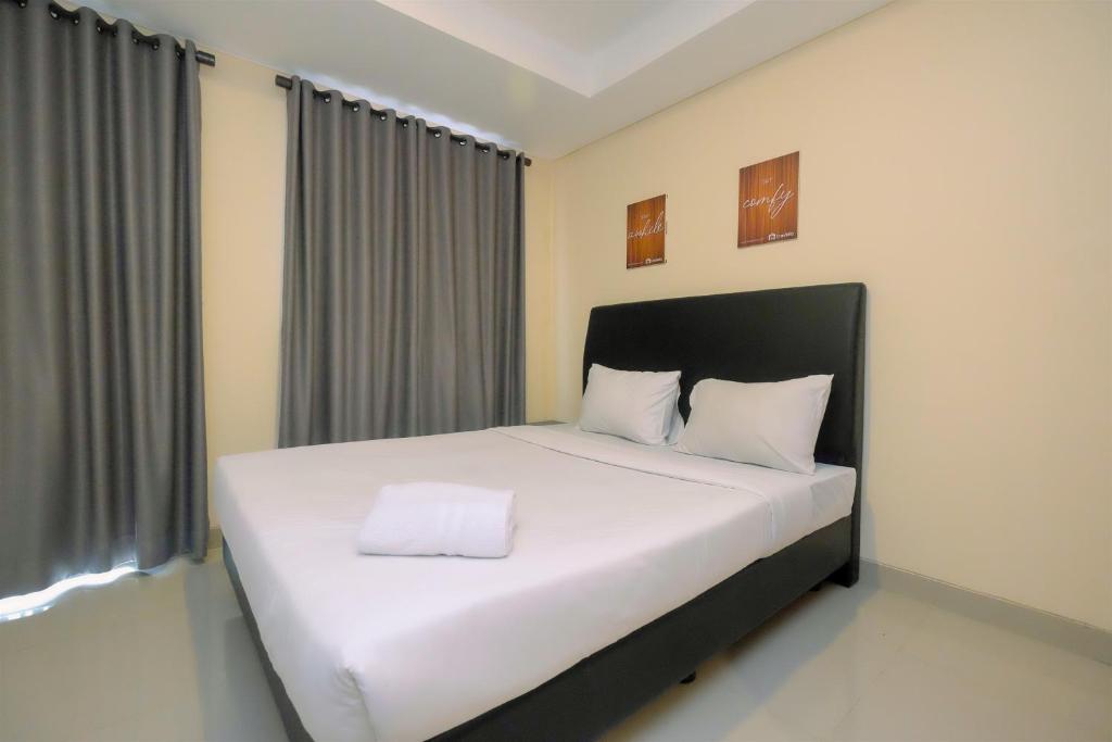 a bedroom with a large bed with white sheets at Studio Kebayoran Icon Apartment near Gandaria City Mall By Travelio in Jakarta