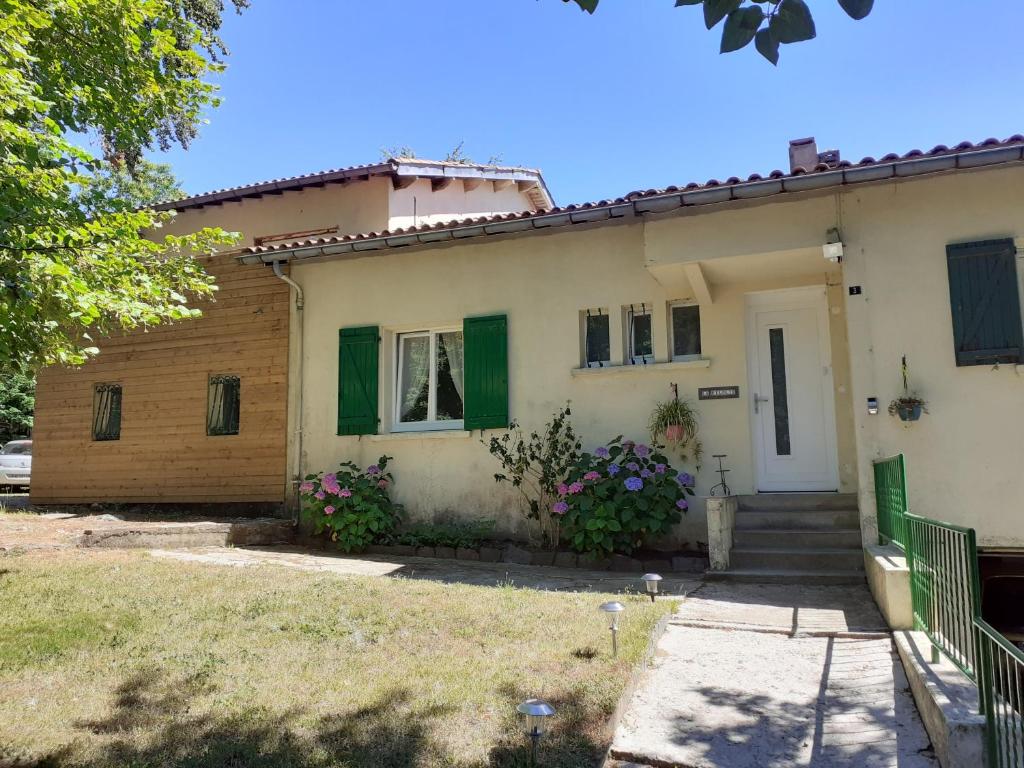 a white house with green shutters and a yard at chez Black and White in Les Martys