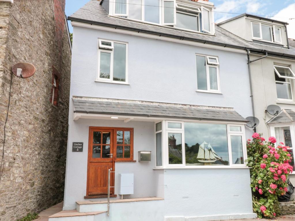 ein weißes Haus mit brauner Tür und Blumen in der Unterkunft Anchor Cottage in Salcombe