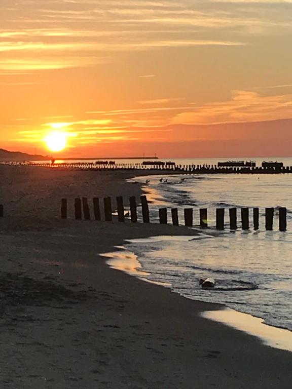 a sunset at the beach with a pier at Ive‘s Gardenia Seaside in Dziwnów