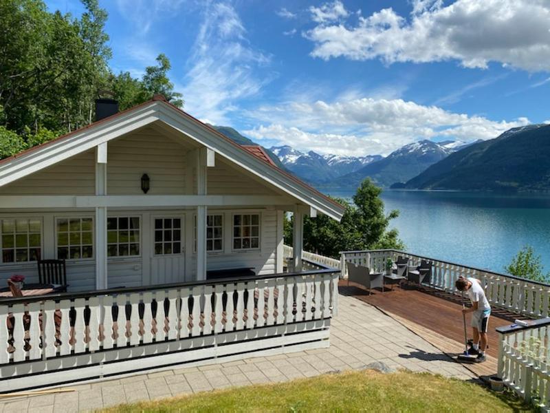 a man standing on a deck next to a house at Faleide Panorama by Homes & Villas in Stryn