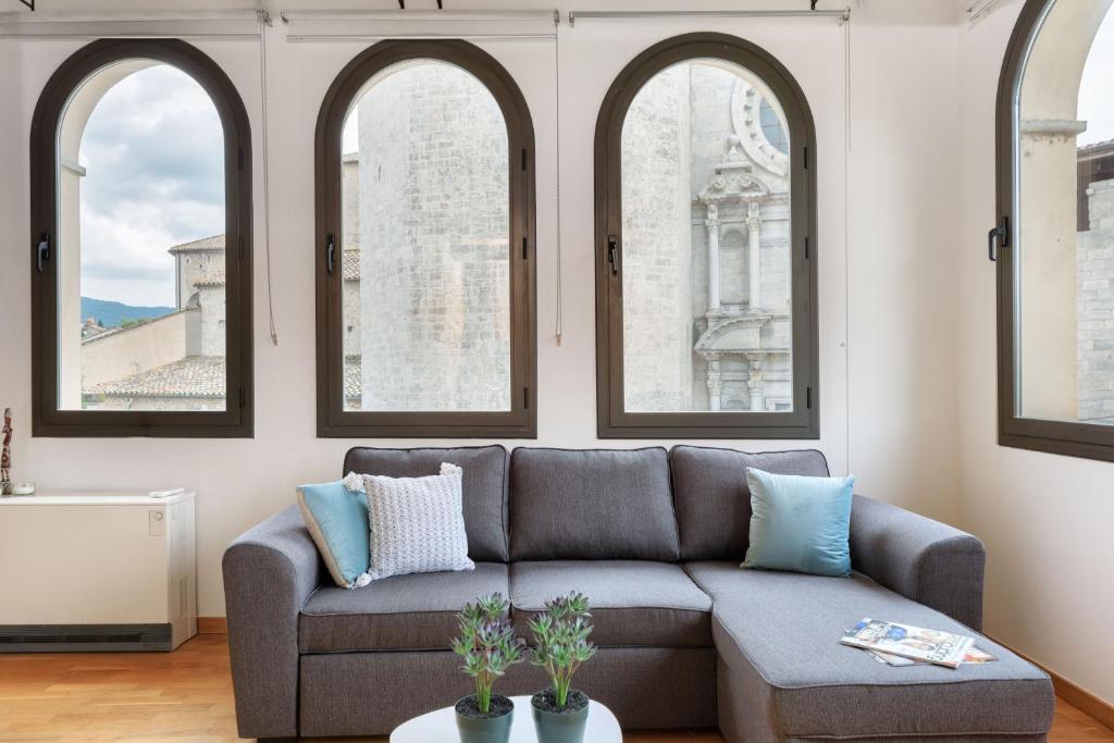 ein Wohnzimmer mit einem Sofa und 3 Fenstern in der Unterkunft Flateli Sant Fèlix in Girona