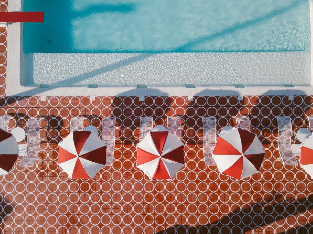 a wall with four umbrellas on top of a pool at Romeos Ibiza - Adults Only in San Antonio Bay