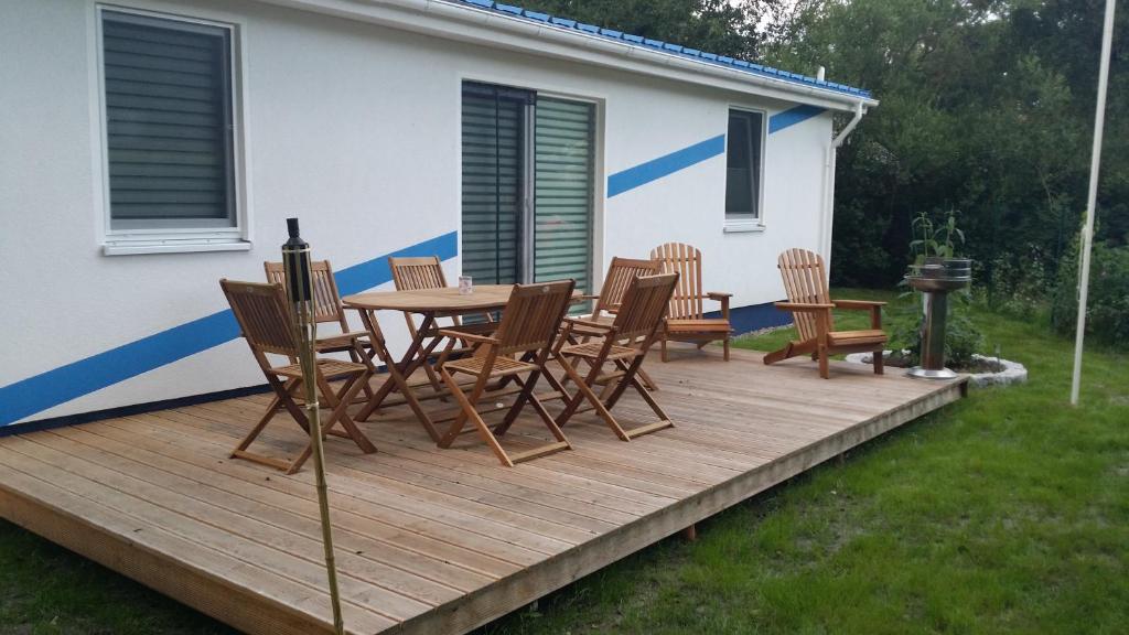 eine Holzterrasse mit einem Tisch und Stühlen darauf in der Unterkunft Ferienhaus „Strandhafer“ in Zingst