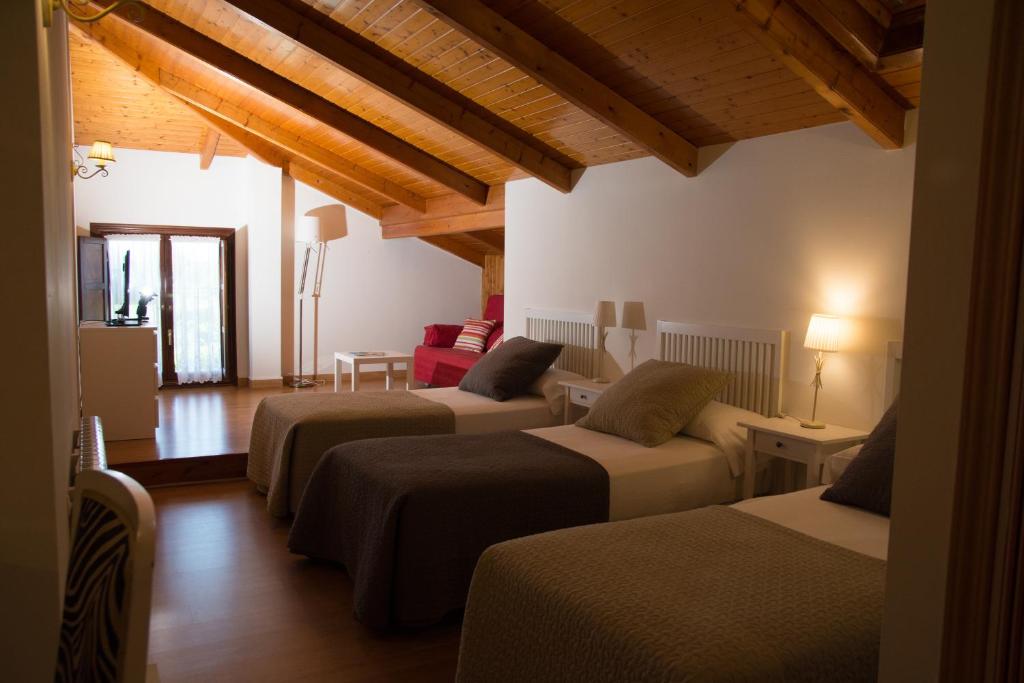 Habitación con 3 camas en una habitación con techos de madera. en Posada de Suesa, en Suesa