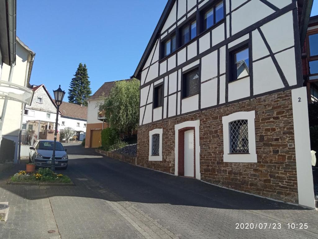 un edificio blanco y negro con un coche aparcado en la calle en Ferienwohnung Windecker Ländchen, en Windeck