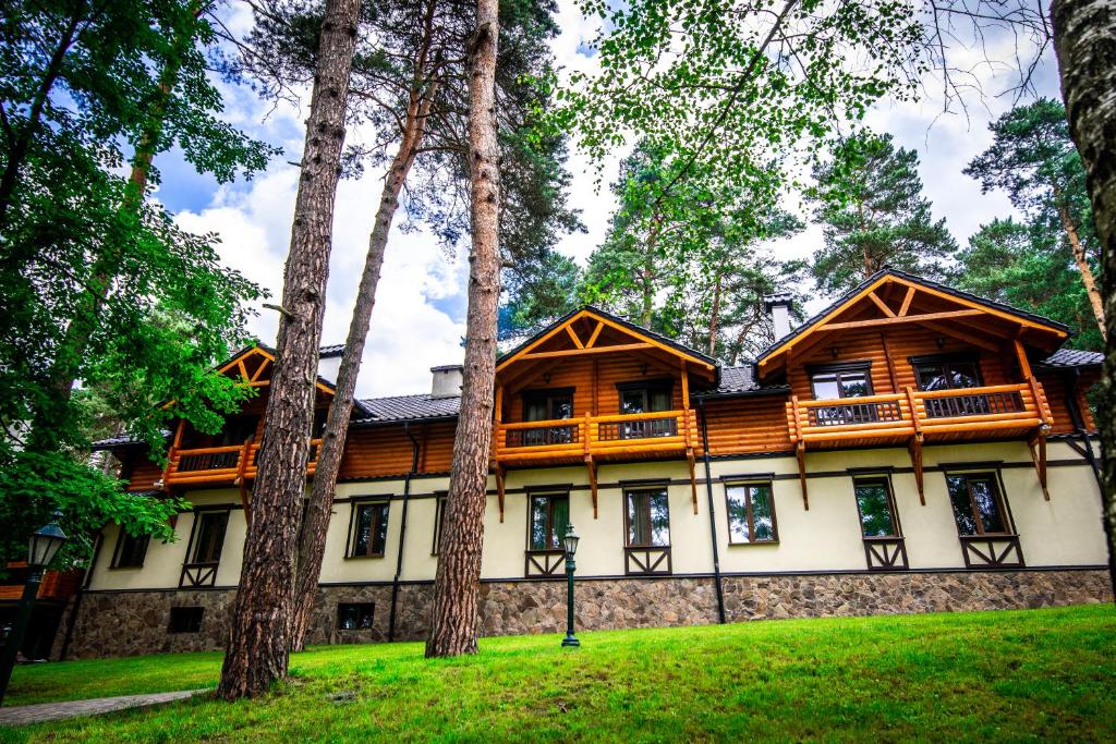 uma grande casa de madeira no meio das árvores em Явір Резорт em Starychi