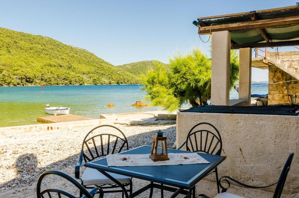 uma mesa azul e cadeiras numa praia com a água em Holiday Home Barbara em Ston