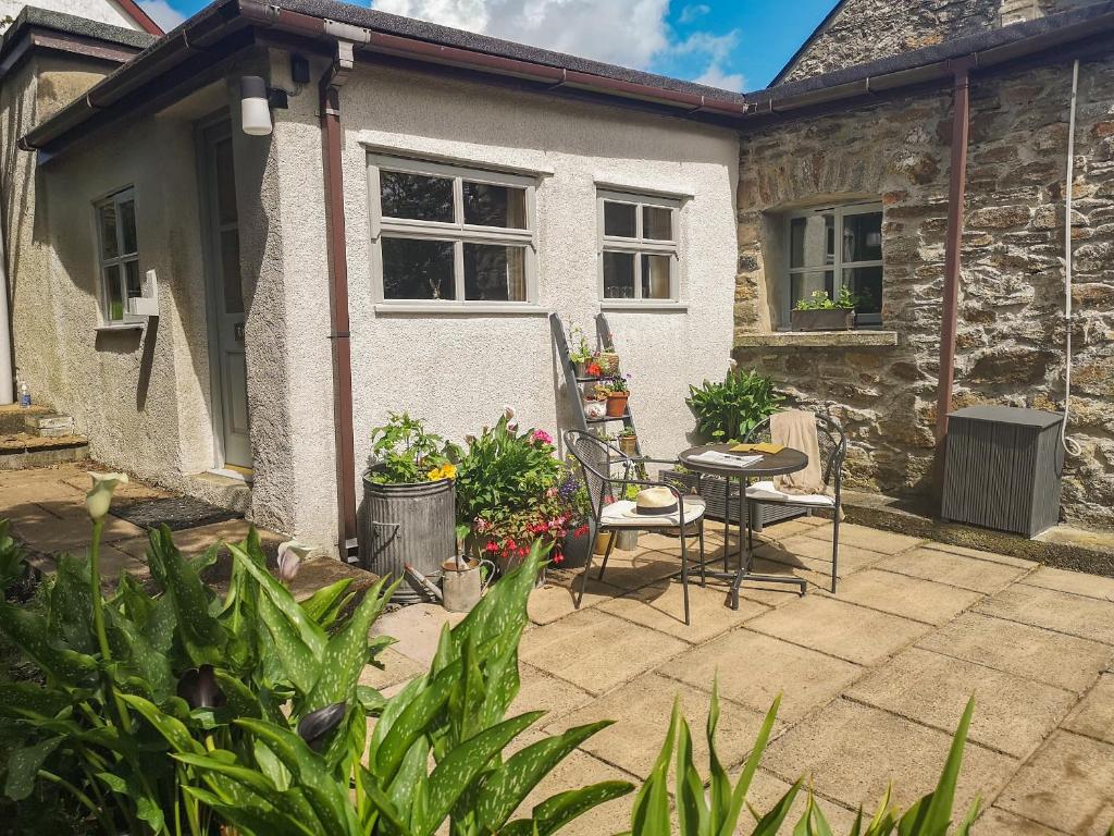 a patio with a table and chairs in front of a house at The Byre in Llandyfrydog