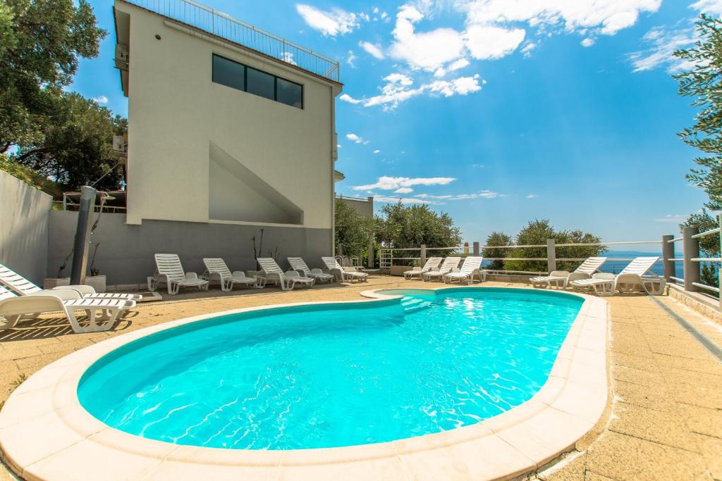 a swimming pool with chairs and a building at Villa Ozzi with 9 bedrooms & private Pool in Makarska