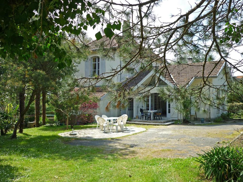 a white house with a table and chairs in the yard at Holiday Home Le chant des milans by Interhome in Ondres