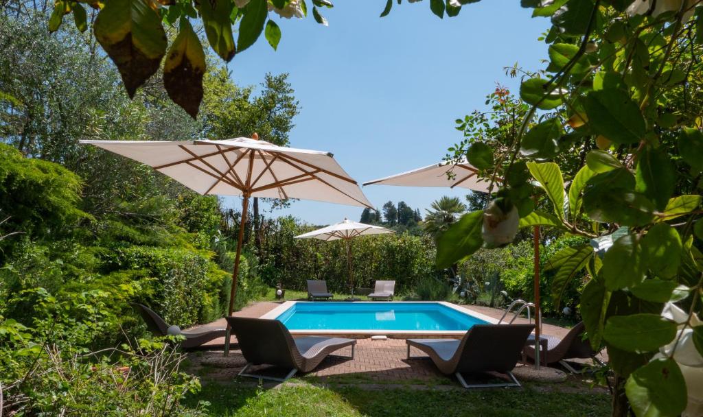 a swimming pool with two umbrellas and two chairs and a table with at Relais Casamassima in Ponte Felcino
