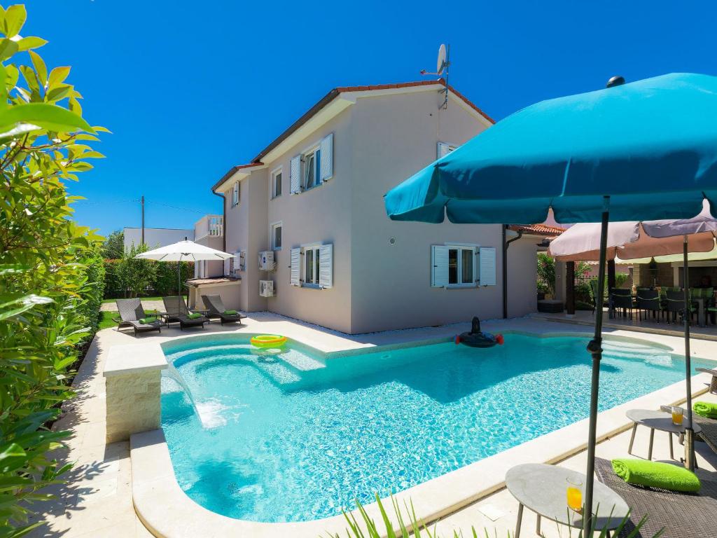 a swimming pool with an umbrella and a house at Holiday Home Villa Valentina by Interhome in Loborika