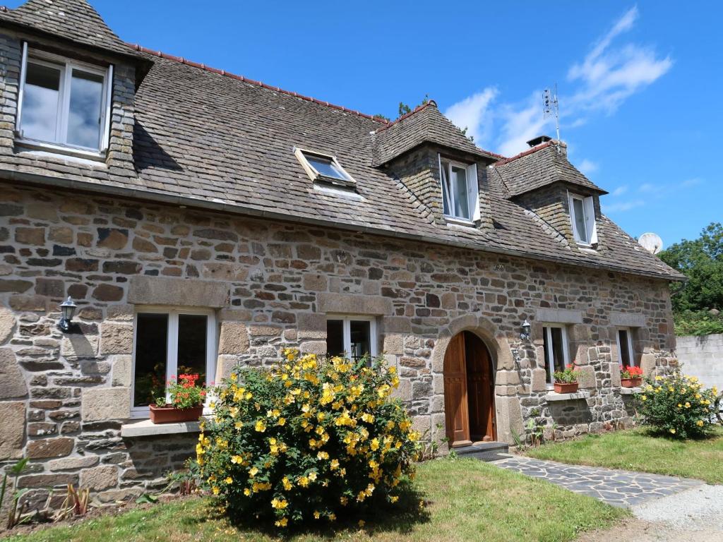une vieille maison en pierre avec des fleurs dans la cour dans l'établissement Holiday Home Pors Ar Goff by Interhome, à Plouégat-Guérand