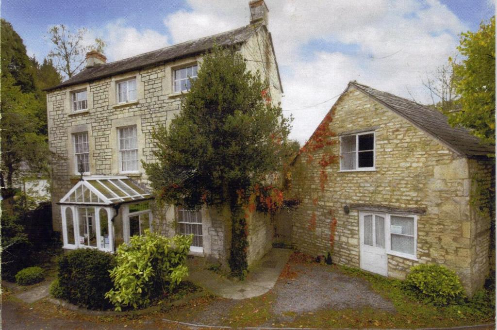 an old stone house with a greenhouse in front of it at The Laurels At Inchbrook in Stroud