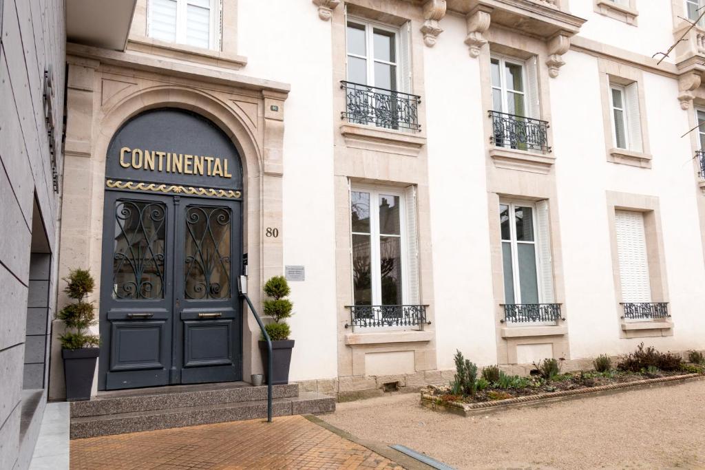 um edifício com uma porta preta em frente em Le Gérémoy em Vittel