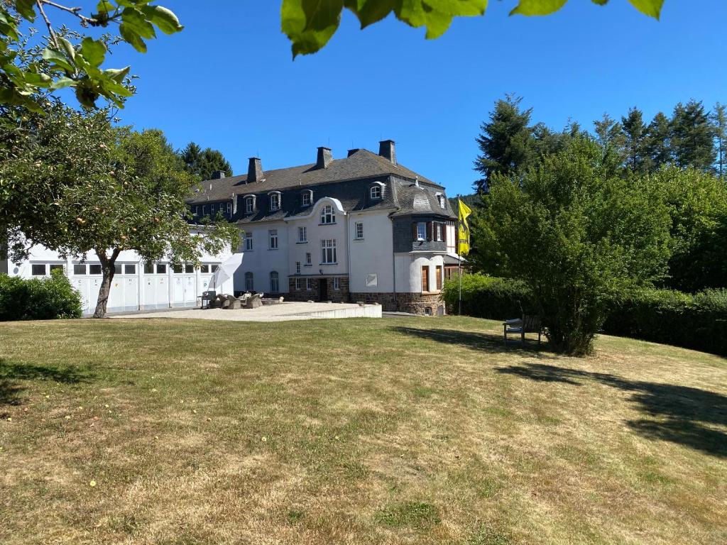 una gran casa blanca con un gran patio en Nürburgring Ferienhaus m. Parkplatz - Klima - Garten und viel Platz, en Adenau