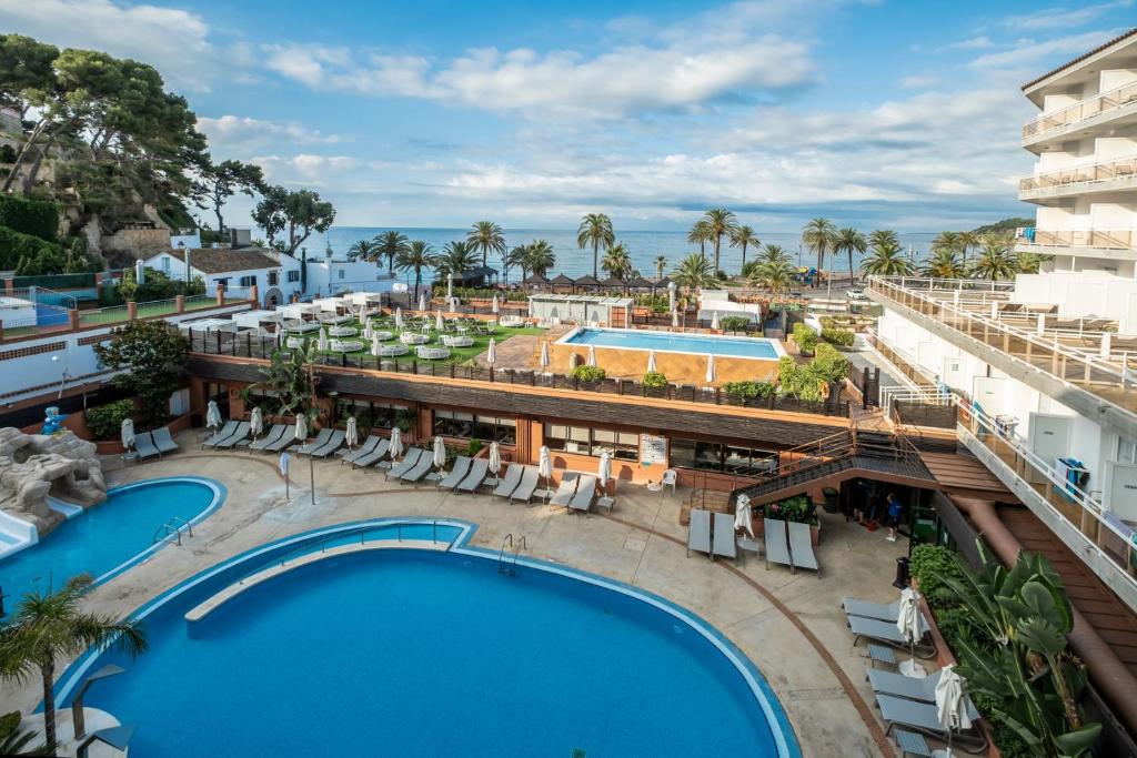 a hotel room with a pool, chairs, and tables at Rosamar & Spa 4*s in Lloret de Mar