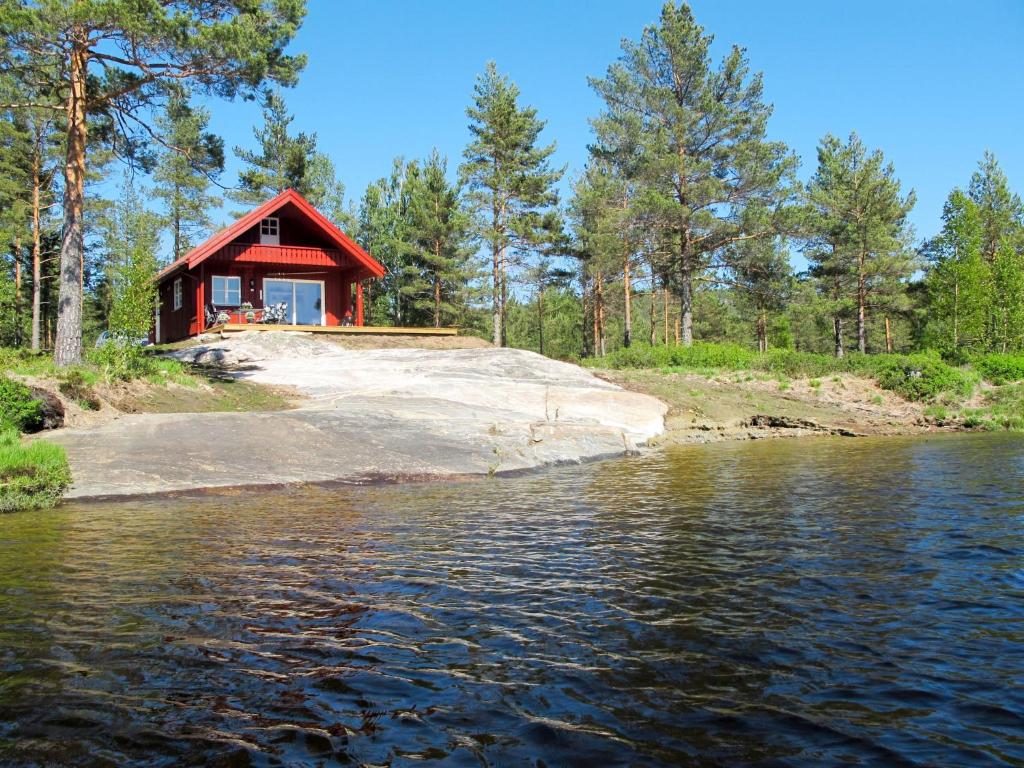 een rode hut aan de oever van een waterlichaam bij Chalet Risdalbu - SOO021 by Interhome in Mjåvatn
