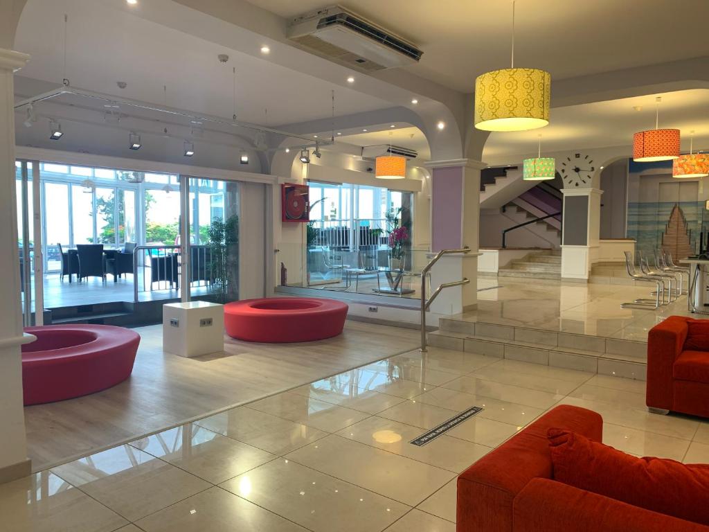 a lobby with red chairs and tables in a building at Aparthotel Los Dragos del Sur in Puerto de Santiago