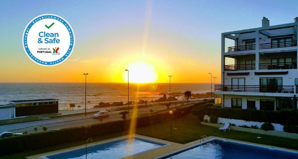 a building with a swimming pool in front of a sunset at Oporto Flag in Vila Nova de Gaia