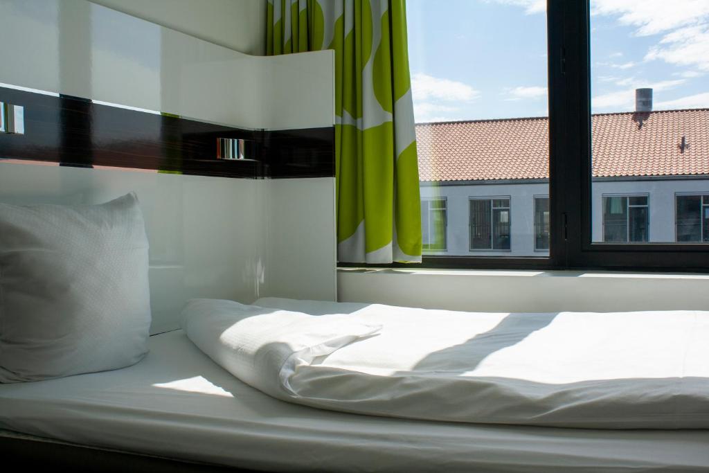 a white bed sitting in a room with a window at Wakeup Copenhagen - Borgergade in Copenhagen