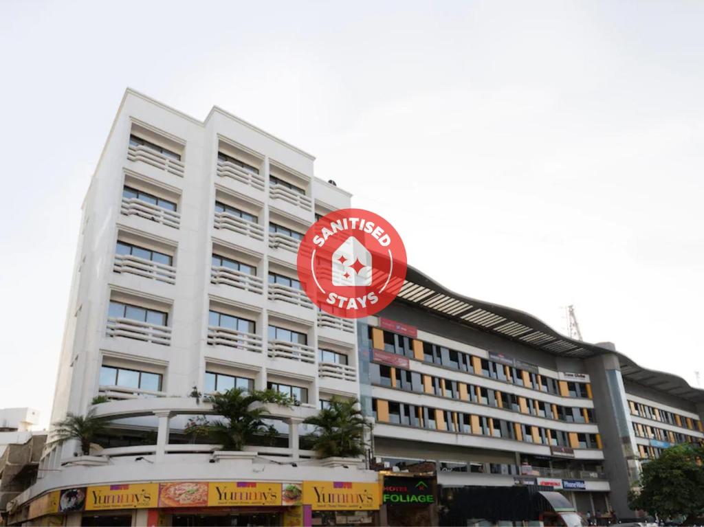 ein großes weißes Gebäude mit einem roten Schild darauf in der Unterkunft Hotel Foliage in Jamnagar