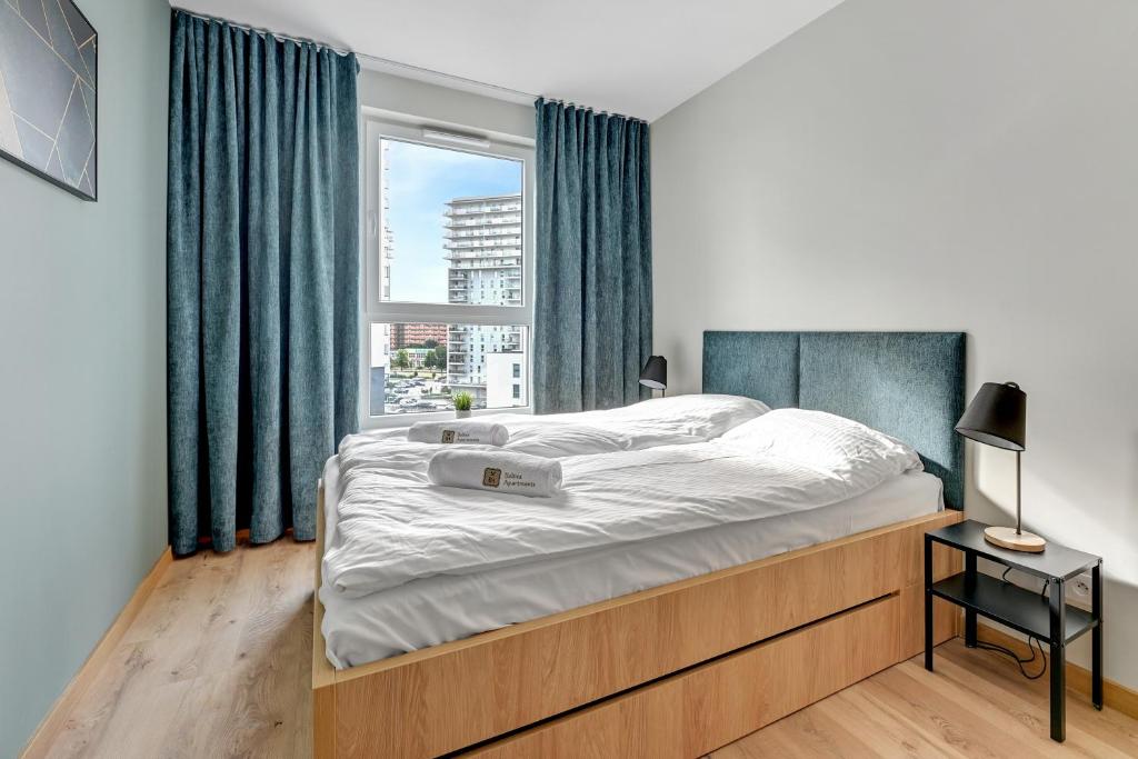 a bedroom with a large bed with a window at Chill Mood by Baltica Apartments in Gdańsk