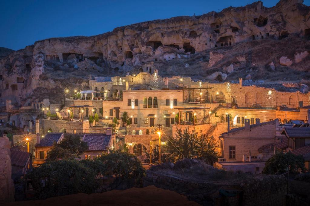 Una ciudad de noche con una montaña en el fondo en Dere Suites Cappadocia, en Ürgüp