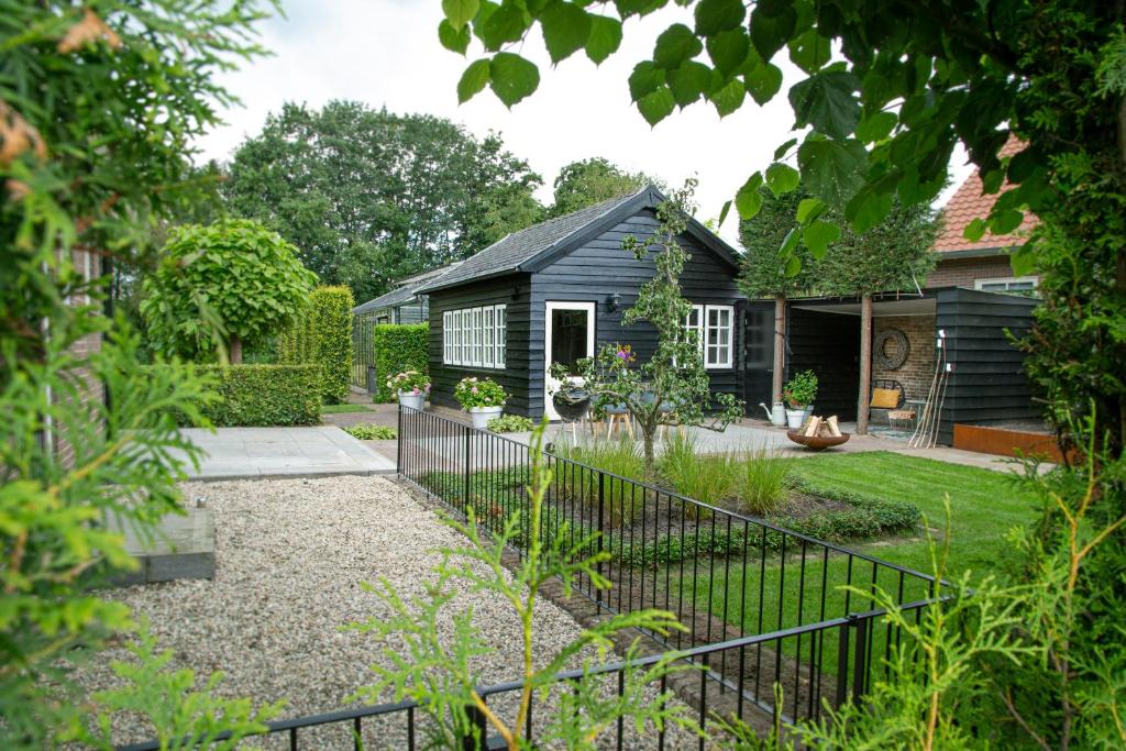 Tukken op de Tol في Velp: حديقة بها منزل أسود وسياج