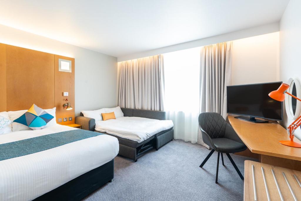 a hotel room with two beds and a desk at Holiday Inn Bournemouth by IHG in Bournemouth