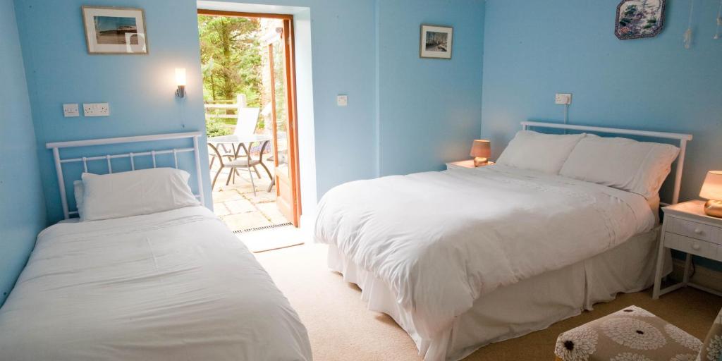 リマバディにあるBallyhenry House and Apartmentsの青いベッドルーム(ベッド2台付)、パティオが備わります。