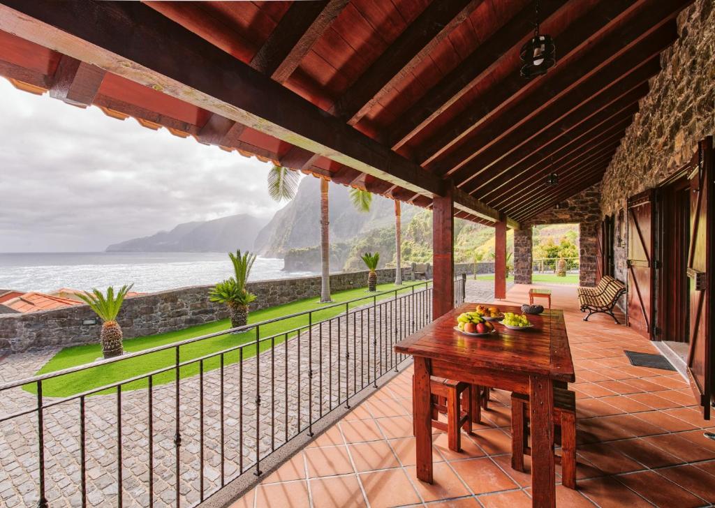 een patio met een tafel en uitzicht op de oceaan bij Seixal Sunny Villa A & B in Seixal