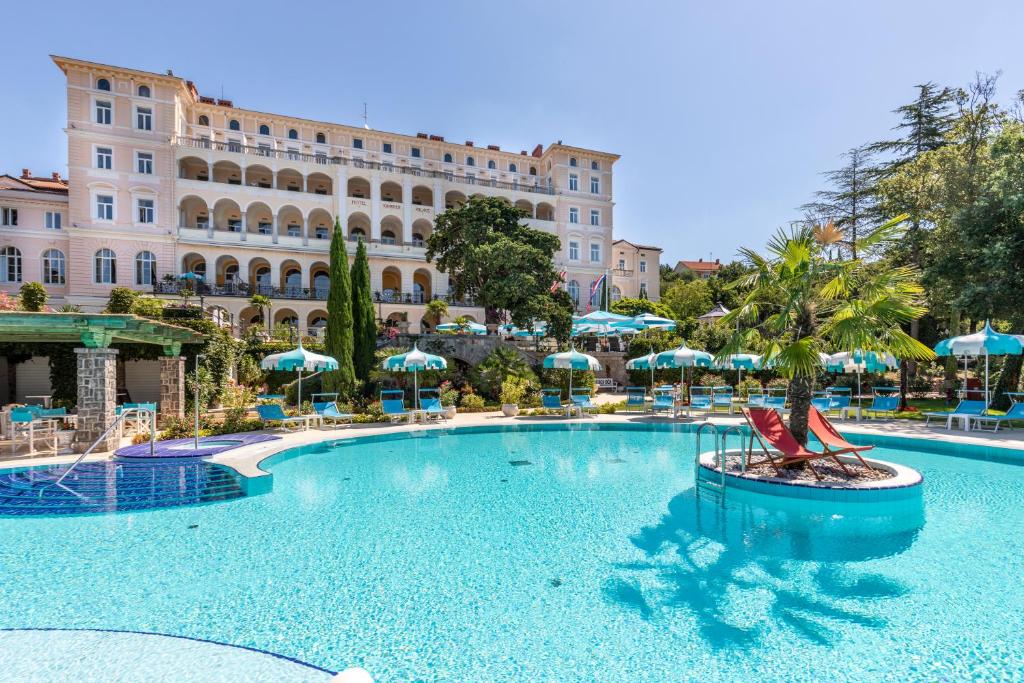 einem großen Pool mit Stühlen und Sonnenschirmen vor einem Gebäude in der Unterkunft Hotel Kvarner Palace in Crikvenica