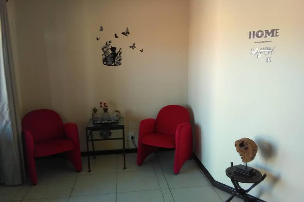 two red chairs in a corner of a room at Oppidam Self Catering in Clanwilliam