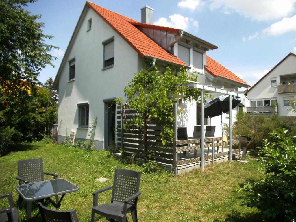 a white house with an orange roof and chairs at Ferienhaus Kettler II in Muhr amSee