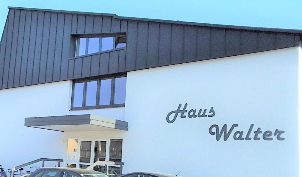 a white and black building with cars parked in front of it at Appartementhäuser Herbert und Walter in Bad Füssing