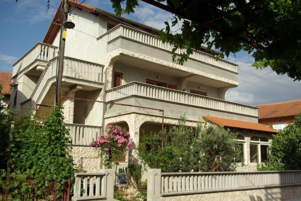 een wit huis met een wit hek ervoor bij Vodice, apartmani Buntić in Vodice
