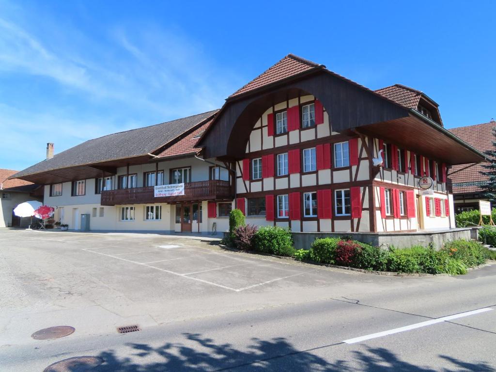 een gebouw met rode en witte ramen en een parkeerplaats bij Gasthof Schwanen Radelfingen in Radelfingen