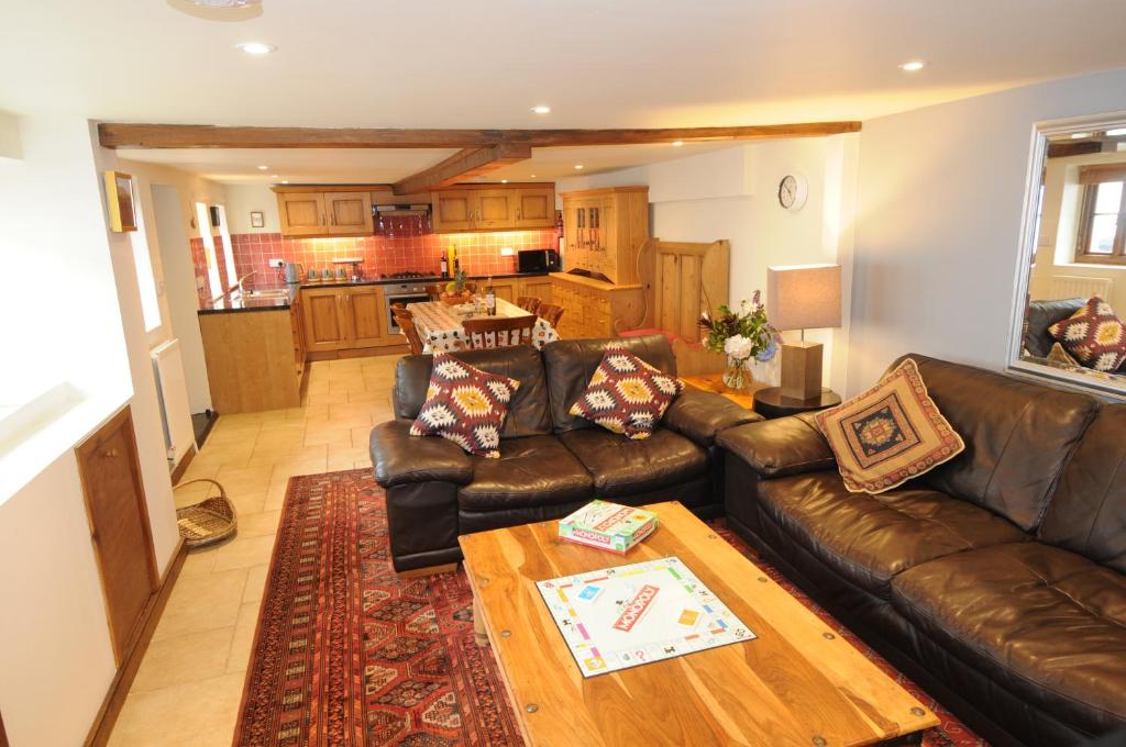 a living room with a leather couch and a table at Church Cottage in Charmouth