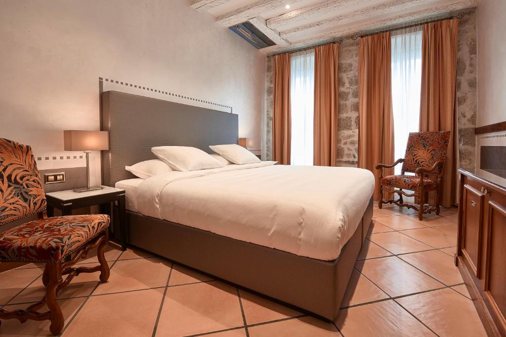 a bedroom with a large bed and a chair at Hotel d'Allèves in Geneva