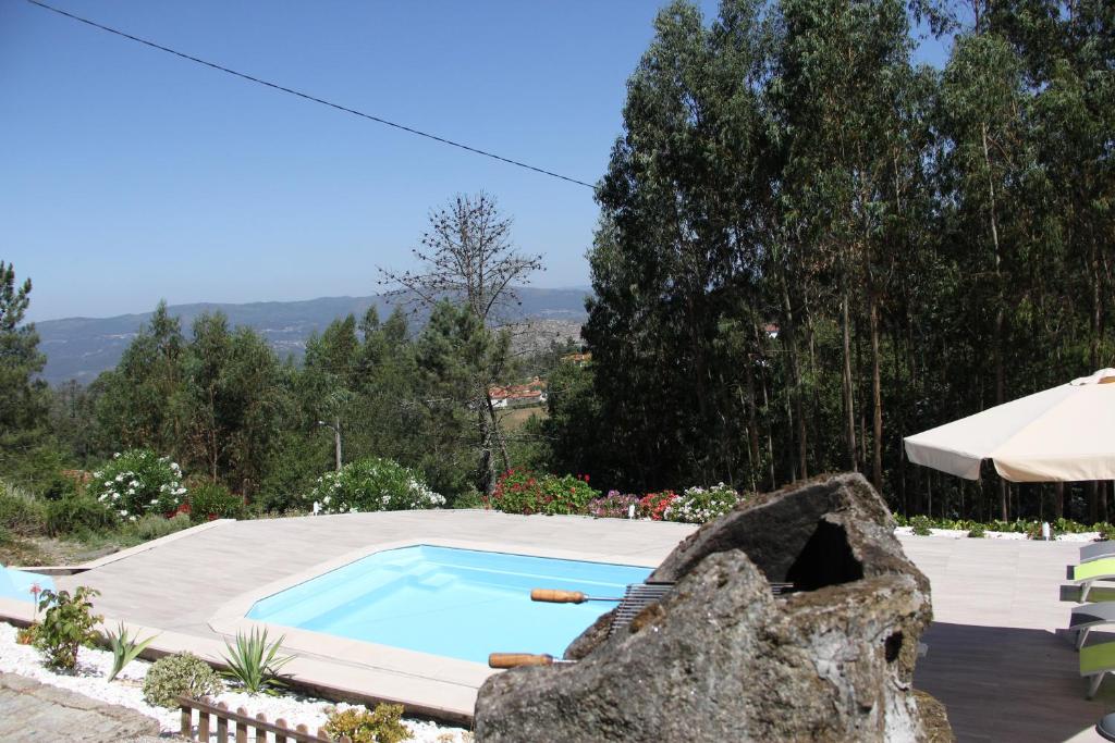 a swimming pool in a yard with a large rock at Casa Quelha da Presa in Espinho